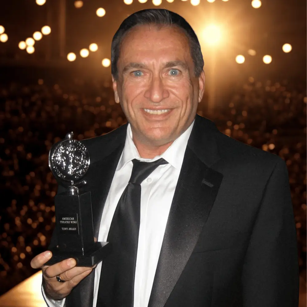 Carl Moellenberg smiling in a tuxedo while holding his Tony Award